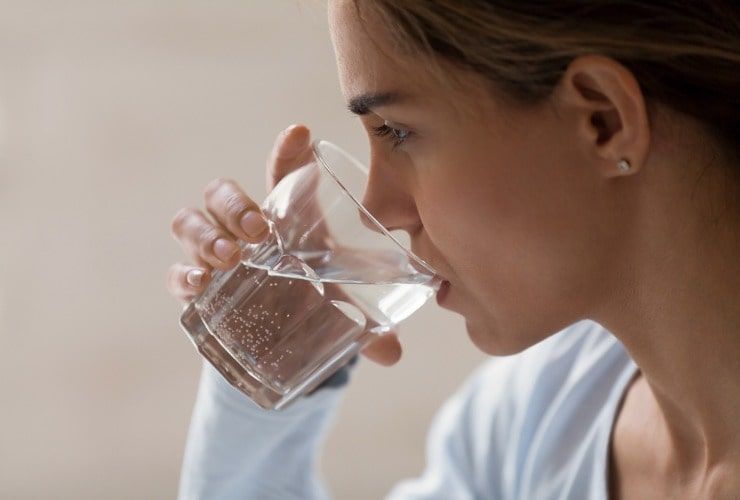 Donna beve un bicchiere di acqua