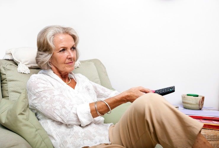Donna anziana utilizza telecomando tv a casa 