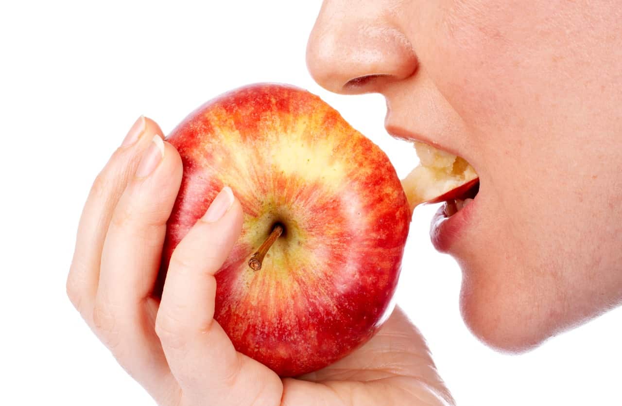 Donna addenta mela con la buccia