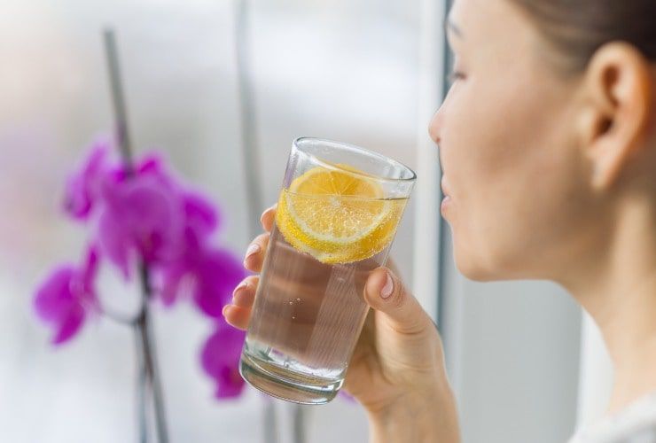 Donna beve un bicchiere di acqua e limone