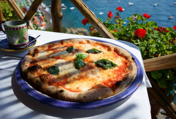 Margherita pizza serveras på balkongen med utsikt över havet 