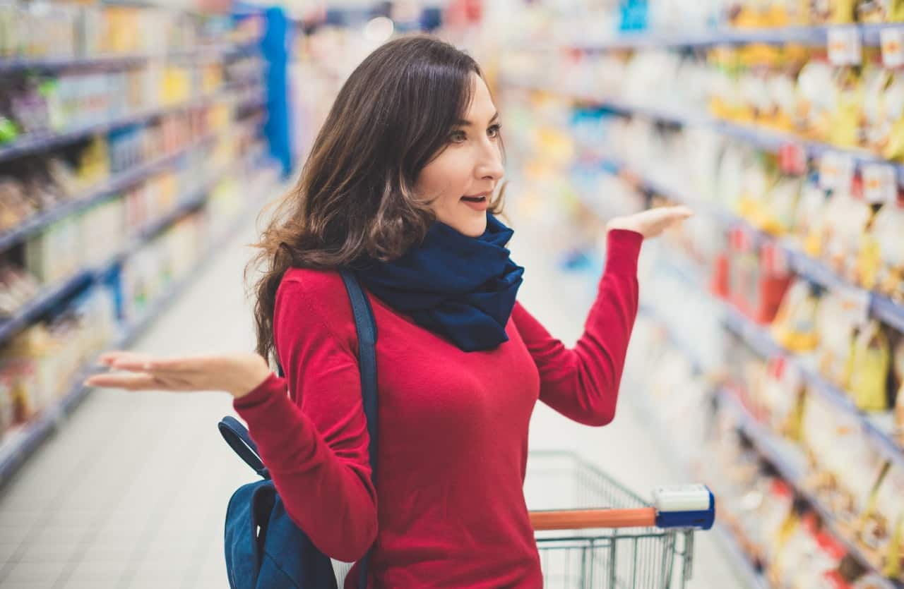 Truffa al Supermercato, giovane donna bruna guarda scaffale al supermercato