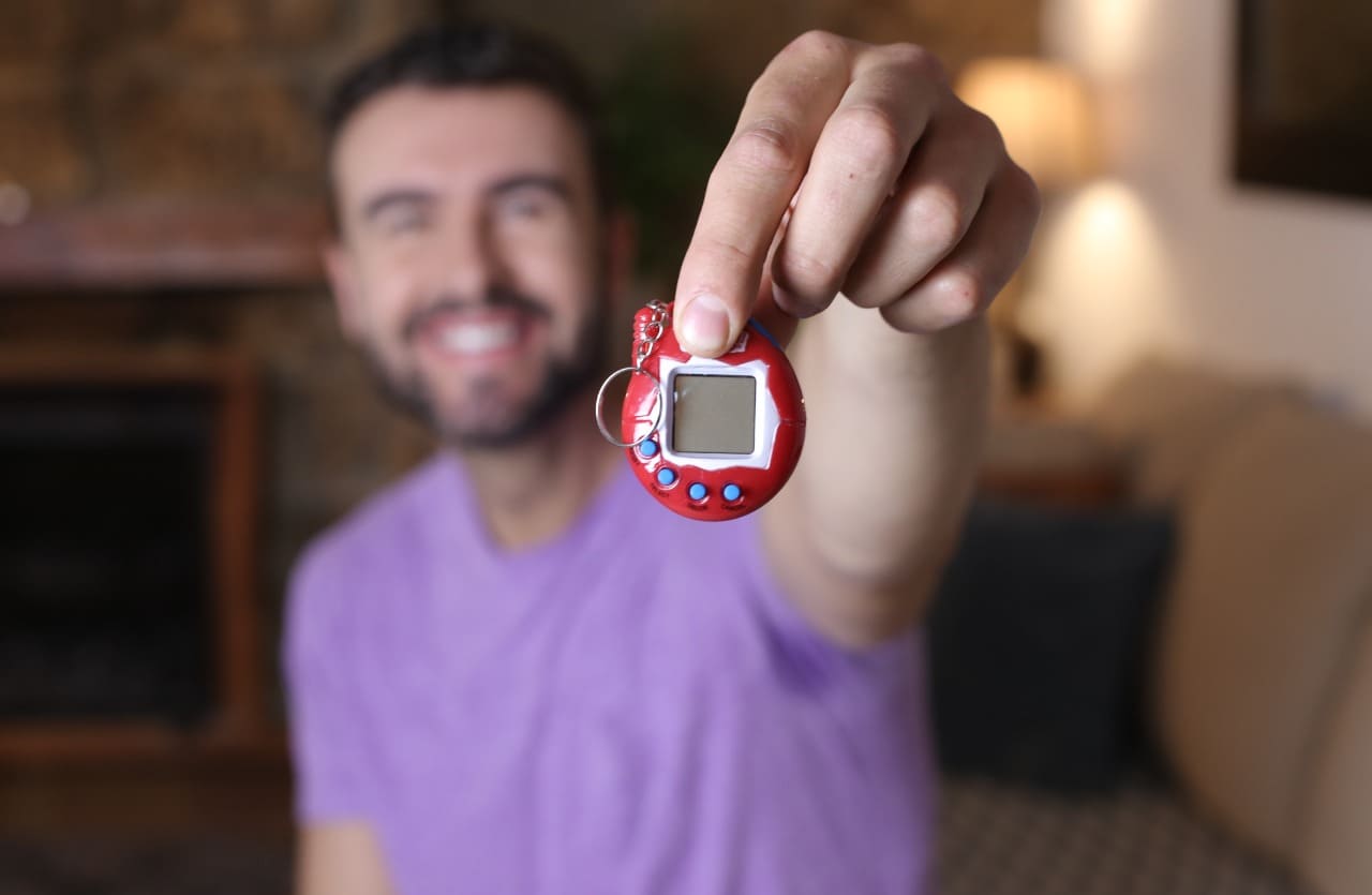 Uomo tiene in mano giocattolo Tamagotchi