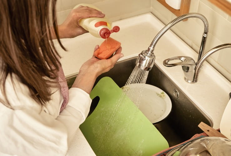 Donna lava piatti e il tagliere con il sapone