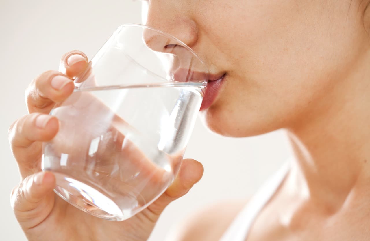 Giovane donna beve un bicchiere di acqua
