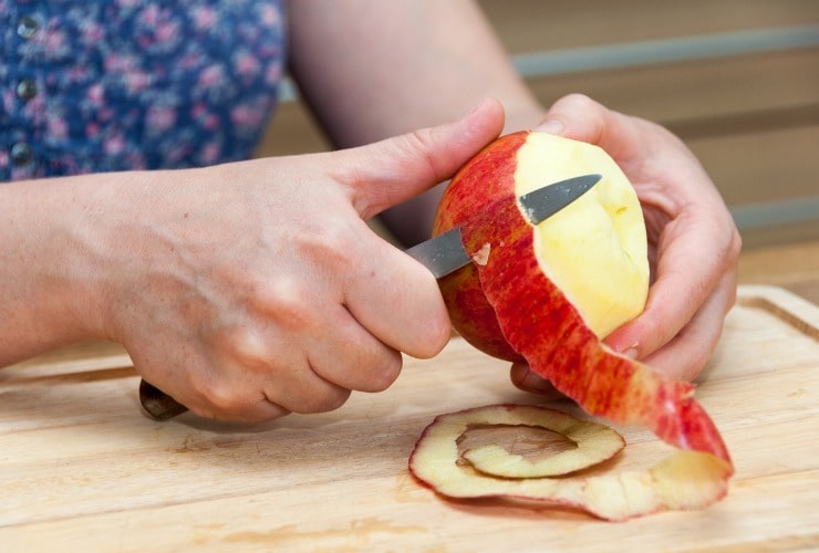 Mani sbucciano una mela