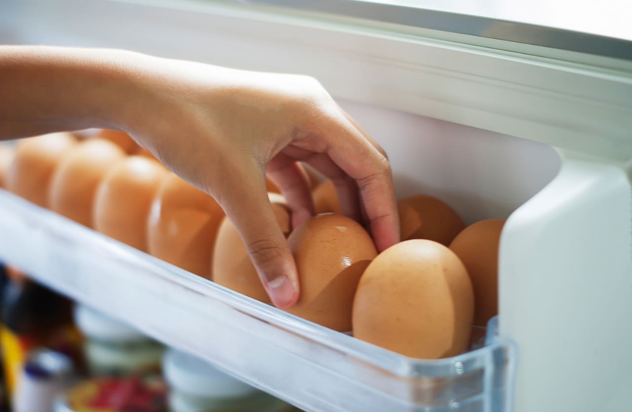 Mano prende uova dal frigorifero