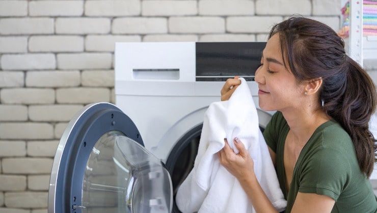 Donna annusa bucato profumato dalla lavatrice 