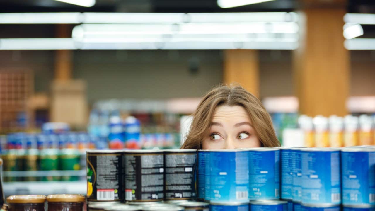 Giovane donna tra scaffali del supermercato