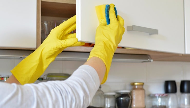 Donna in guanti gialli pulisce cucina 