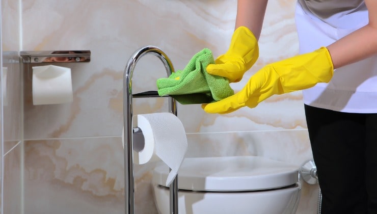 Donna con guanti gialli disinfetta il bagno