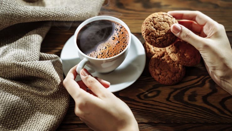 Mani con tazza di caffè e biscotto 