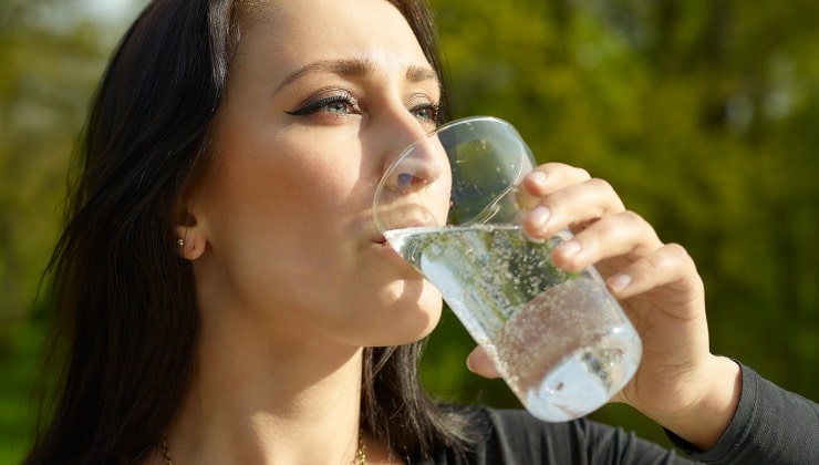 Donna beve un bicchiere di acqua frizzante