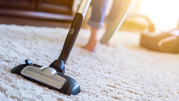 Donna pulisce il tappeto in casa 