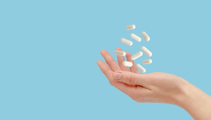 Mano con tabletas blancas