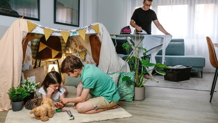 Uomo stira accanto i bimbi giocano